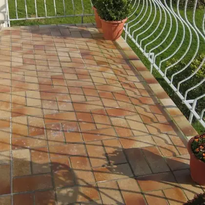 Balkon mit Metallgeländer vor der Sanierung: fleckige Terrakotta-Fliesen, verwitterte Fugen