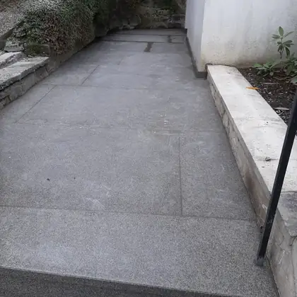 Terrassenweg am Haus nach der Sanierung: großformatige graue Platten mit sauber gesetzter Stufe – InnoStone Treppensanierung