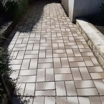 Terrassenweg am Haus vor der Sanierung: alte beige Betonsteine mit Fugenbewuchs