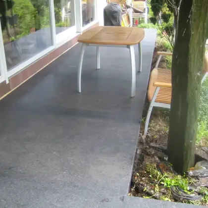 Überdachte Terrasse nach der Sanierung: dunkelgraue großformatige Natursteinplatten – InnoStone Treppensanierung