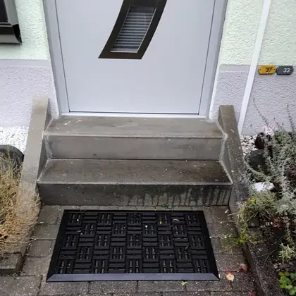 Hauseingang mit zwei Stufen vor der Sanierung: ausgetretene, stumpfe Betonstufen