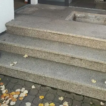 Breite Eingangstreppe mit Podest vor der Sanierung: ausgewaschener Altbelag mit offener Aussparung