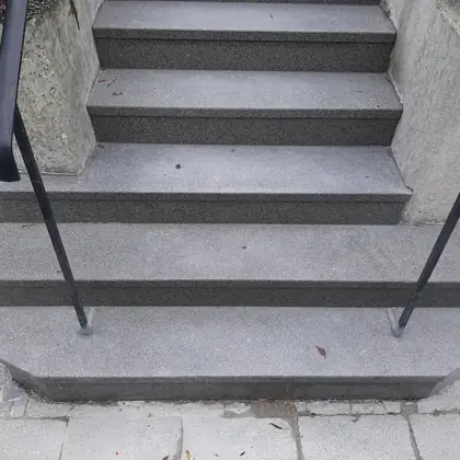 Hauseingang mit gerundetem Antritt nach der Sanierung: Anthrazit-Granit, schwarze Handläufe neu gesetzt – InnoStone Treppensanierung