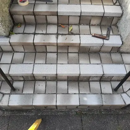 Hauseingang mit gerundetem Antritt vor der Sanierung: alte Betonplatten, unebene Trittflächen