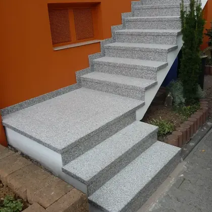 Außentreppe an oranger Fassade nach der Sanierung: hellgrauer Granit, Antritt in voller Breite – InnoStone Treppensanierung