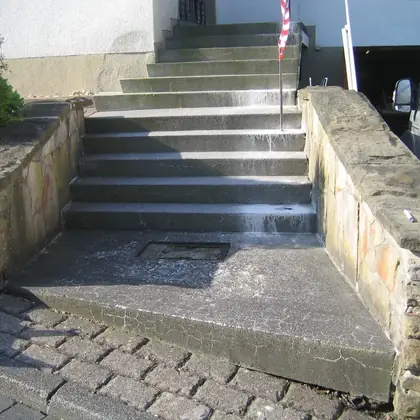 Breite Treppe zwischen Sandsteinmauern vor der Sanierung: dunkel vermooster, nasser Beton