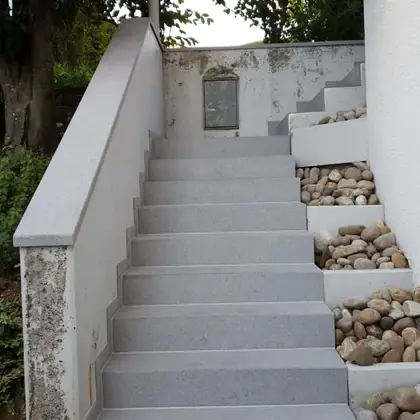 Lange Gartentreppe am Hang nach der Sanierung: hellgrauer Granit, Wange mit abgesetzt – InnoStone Treppensanierung