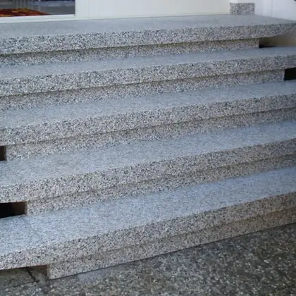 Freitragende Treppe vor der Hecke nach der Sanierung: hellgrauer Granit, Stufen einzeln aufgelegt – InnoStone Treppensanierung