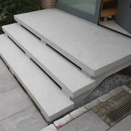 Hauseingang mit Schmiedegeländer nach der Sanierung: feinkörniger heller Granit mit neuem Podest – InnoStone Treppensanierung