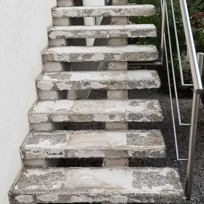 Freitragende Stufen am Kiesbeet vor der Sanierung: stark erodierter Beton, sichtbare Zuschlagkörner