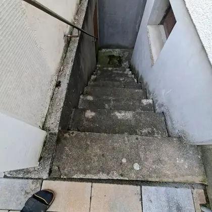 Enger Kellerabgang vor der Sanierung: bröckelnder Beton mit Moosbewuchs