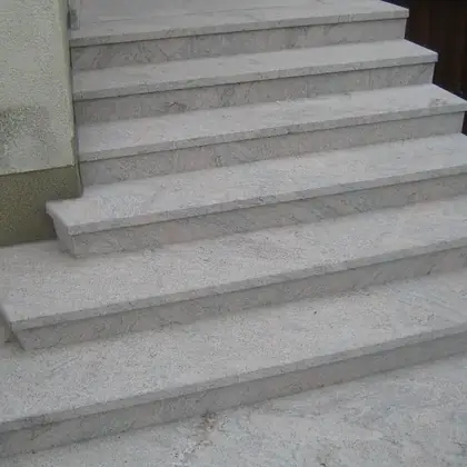 Breite L-Treppe am Eingang nach der Sanierung: hellgrau-beiger Naturstein mit klarer Kante – InnoStone Treppensanierung