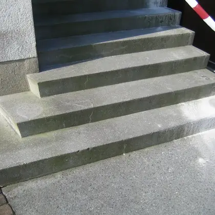 Breite L-Treppe am Eingang vor der Sanierung: grün verwitterte, grobe Betonblöcke