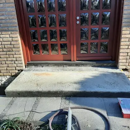Eingangspodest an der Doppeltür vor der Sanierung: schmucklose, fleckige Betonplatte