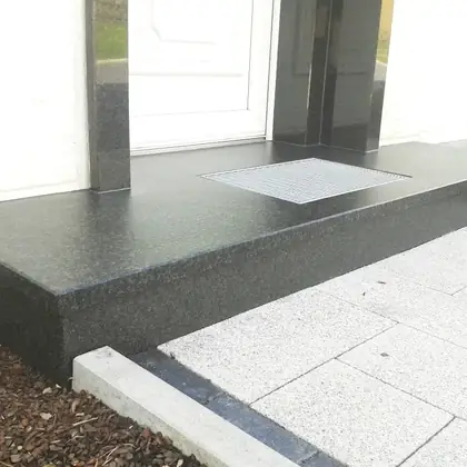 Eingangspodest mit Stufe nach der Sanierung: dunkelgrauer, polierter Granit mit sauberer Kante – InnoStone Treppensanierung